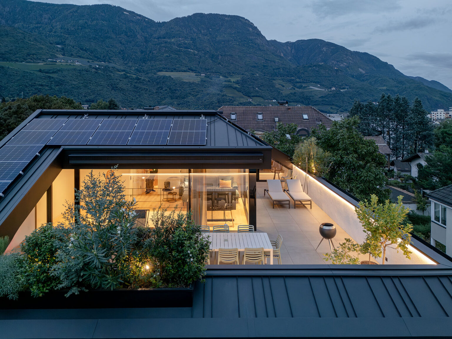Haus SP: Dachterrasse mit verglastem Wohnraum in der Abenddämmerung